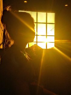 a woman standing in front of a window with the sun shining through