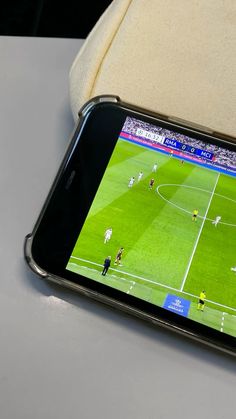 a cell phone sitting on top of a table next to a soccer ball game screen