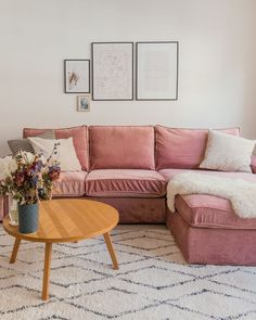 a living room with pink couches and white rugs on the floor next to a coffee table