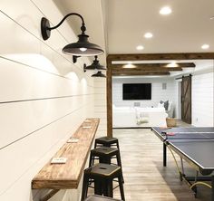 an indoor ping pong table in a room with white walls and wood flooring