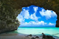 the view from inside an ocean cave looking out at the water and clouds in the sky