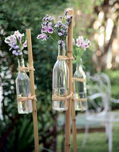 three vases with flowers in them are hanging from a wooden stand on the grass