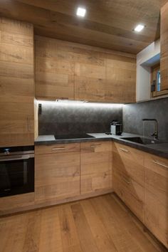 an empty kitchen with wooden cabinets and black counter tops, along with wood flooring