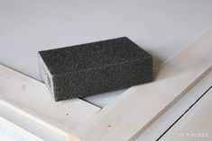 a piece of black foam sitting on top of a window sill next to a wooden frame