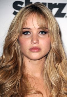 a close up of a person with long blonde hair and blue eyes wearing a black dress