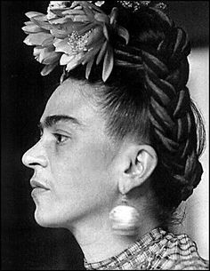 a black and white photo of a woman with flowers in her hair, looking to the side