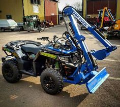 a small blue utility vehicle parked in a parking lot next to a yellow tractor and some other vehicles