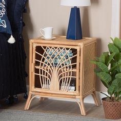 a wicker night stand with a cup on it next to a potted plant