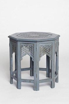 a small table with an intricate design on the top and bottom, sitting in front of a white background