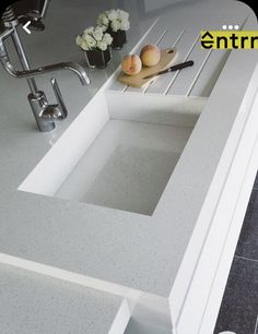 a white sink sitting under a faucet next to a counter top with utensils on it