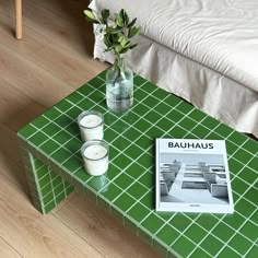 a table with candles and a book on it in front of a bed or couch