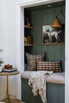 a dog is sitting in the corner of a room next to a table with books on it