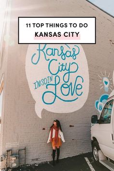 a woman standing in front of a wall with the words kansas city painted on it