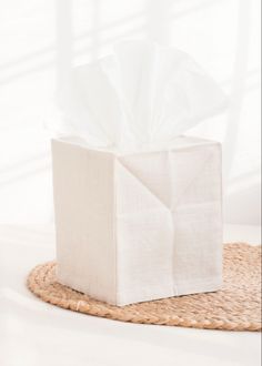 a white tissue box sitting on top of a woven place mat