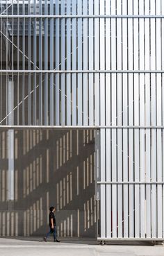 a man is walking down the sidewalk in front of a building with bars on it