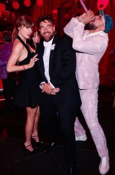 two women and a man pose for a photo in front of a red light at a party