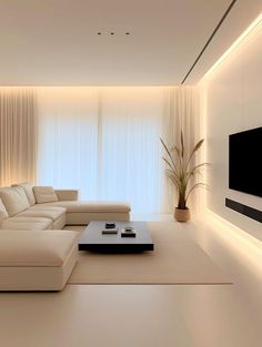 a living room with white couches and a large flat screen tv mounted on the wall