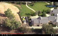 an aerial view of a house with cars parked in the driveway and trees around it