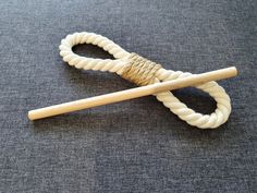 a pair of wooden knitting needles sitting on top of a gray cloth covered floor next to a white rope