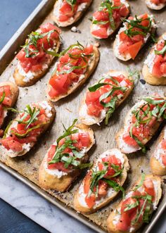 a tray filled with bread topped with tomato slices and green garnish on top