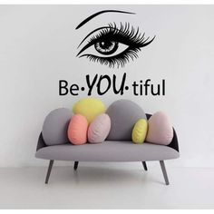 a couch with pillows on it in front of a wall that says be you tiful