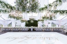 a large dance floor is decorated with white linens and greenery for a wedding reception