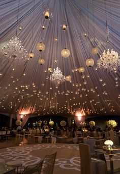 the ceiling is covered with lights and chandeliers for a wedding reception at night