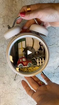 a person holding an alarm clock with toy cars on it's reflection in the mirror