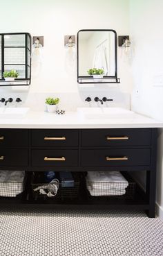 two sinks and mirrors in a bathroom with black cabinetry, white counter tops and tile flooring