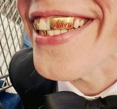 a close up of a person with a gold ring on his teeth and wearing a bow tie