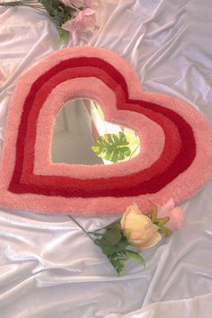 two heart shaped rugs sitting on top of a bed next to flowers and a mirror