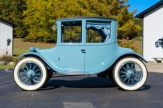 an old blue car parked in a parking lot