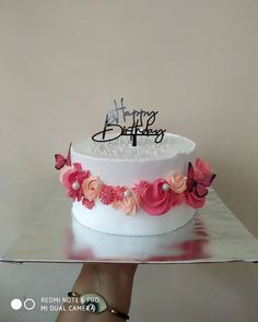 a white cake with pink flowers and a happy birthday topper