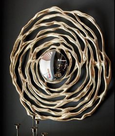 a circular mirror hanging on the wall next to a hook with two candles in it