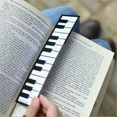 a person is holding an open book with piano keys on it and reading the book