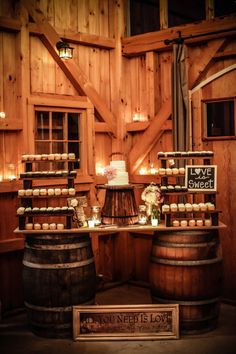 a wedding cake sits on top of a barrel in front of some wooden barrels with candles