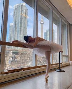 a ballerina is standing in front of a window