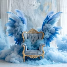 an ornate chair with blue feathers on it in front of a white wall and window