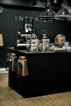 an interior store with black walls and wooden flooring, lanterns hanging from the ceiling