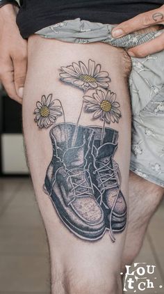 a man with a tattoo on his leg has a boot and daisies in it