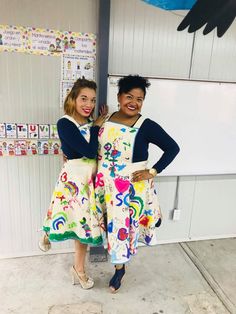 two women standing next to each other in front of a whiteboard