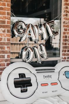 a video game controller sitting on top of a table in front of a window with balloons