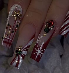 a woman's hand with red and white nail polish on it, decorated with christmas decorations