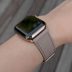 an apple watch on someone's wrist wearing a tan leather band with gold accents