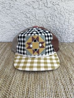 a hat with a patchwork design on it sitting on a table next to a wall