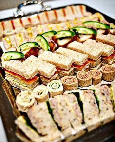 an assortment of sandwiches and cucumbers on a tray