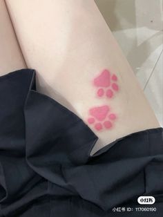 a woman's arm with pink ink on it and paw prints in the background