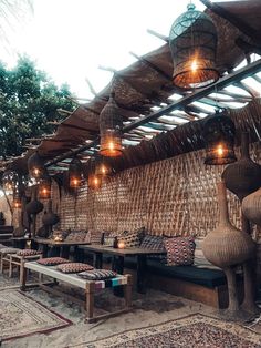 an outdoor seating area with lights hanging from the ceiling and wicker furniture on display