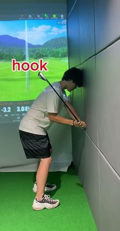 a man holding a golf club in front of a large screen with the words hook on it