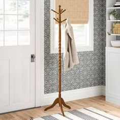 a coat rack in the corner of a room with blue wallpaper and wooden flooring